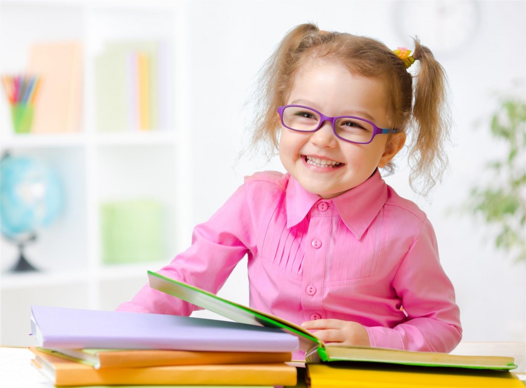 kid in eyeglasses or spectacles reading books in her room